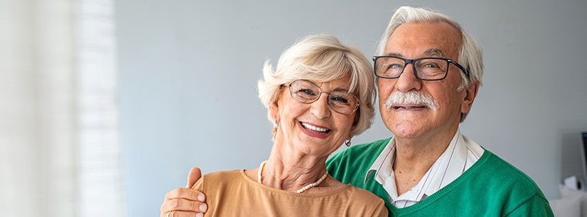 a senior couple stands together in their senior apartment