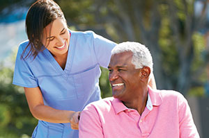 A caregiver pushes an older man in a wheelchair