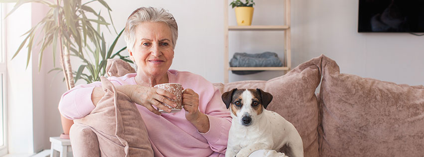 a senior woman sits on her couch with a dog