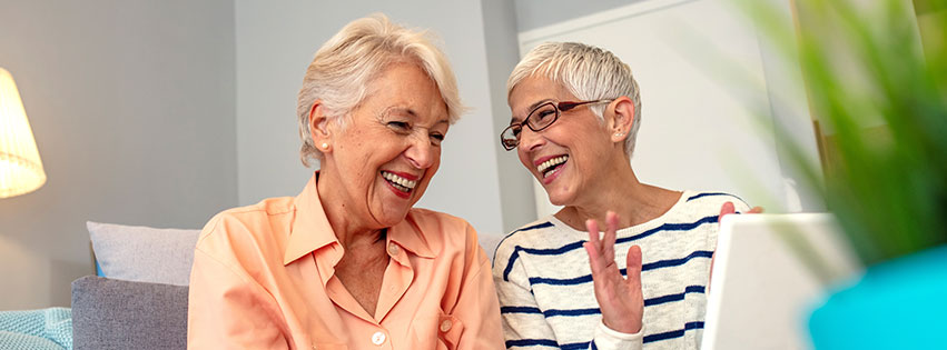 two senior females laugh in their senior living community