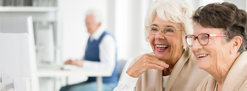 two senior women use a computer together