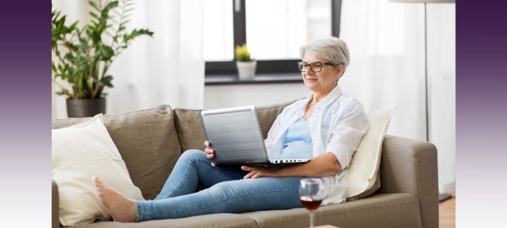 blog_RRCP_when-is-the-right-time-for-independent-living Happy senior woman laying on a couch using her laptop in senior living apartment researching when is the right time for independent living